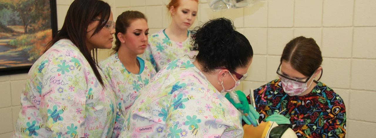 Dental Students working on a mannequin head's teeth