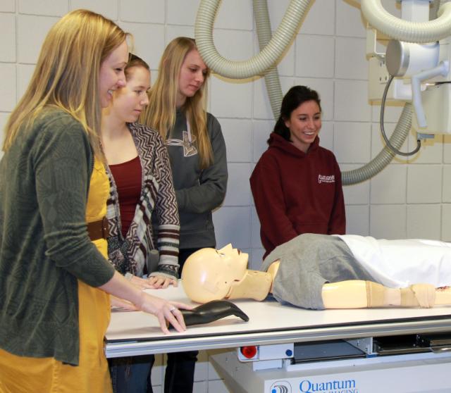 .Radiology teachers and students setting up an x-ray using a mannequin.