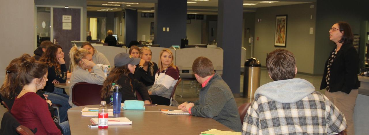 Students at table listening to instructor.