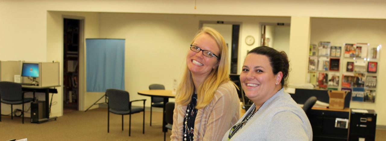 Staff members standing at sitting at desk smiling at camera.