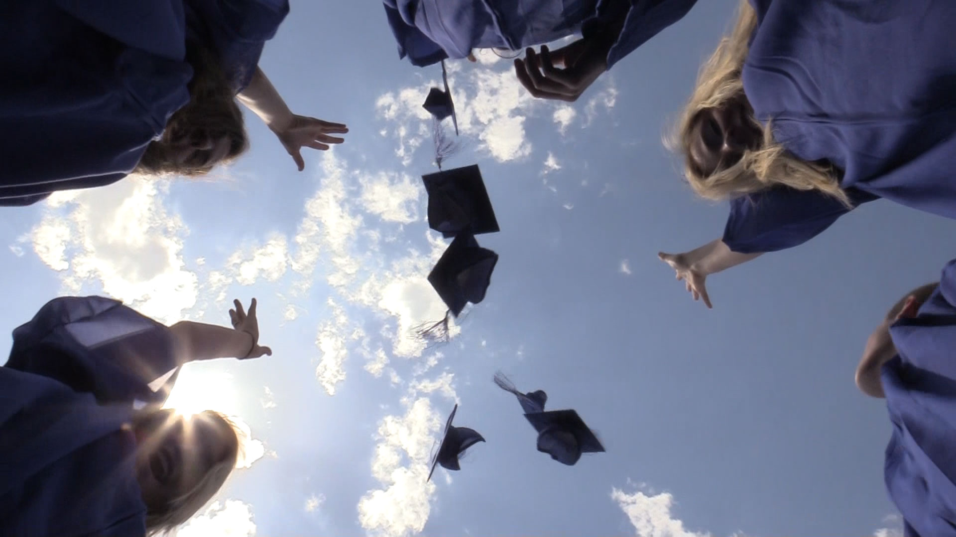 Group of Students at graduation tossing graduation caps into air