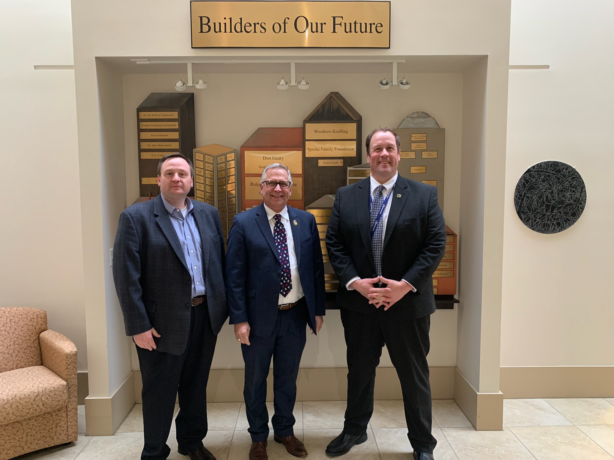 Three men in front of a wall.