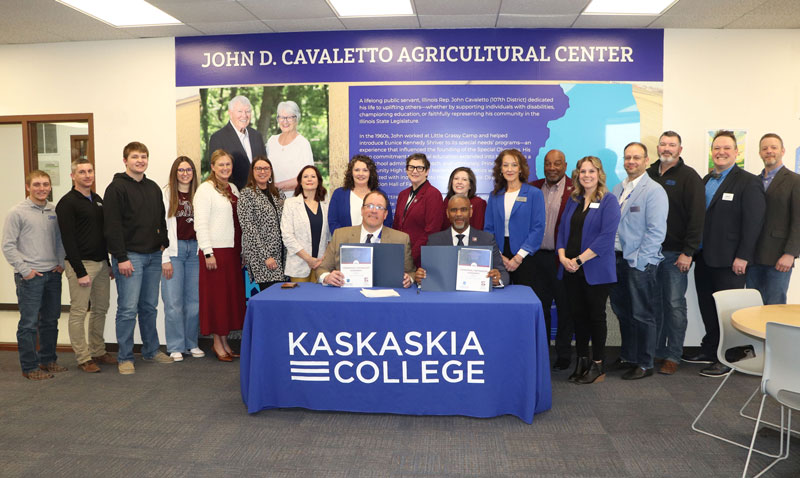 Adults gathered behind a table for agreement signing